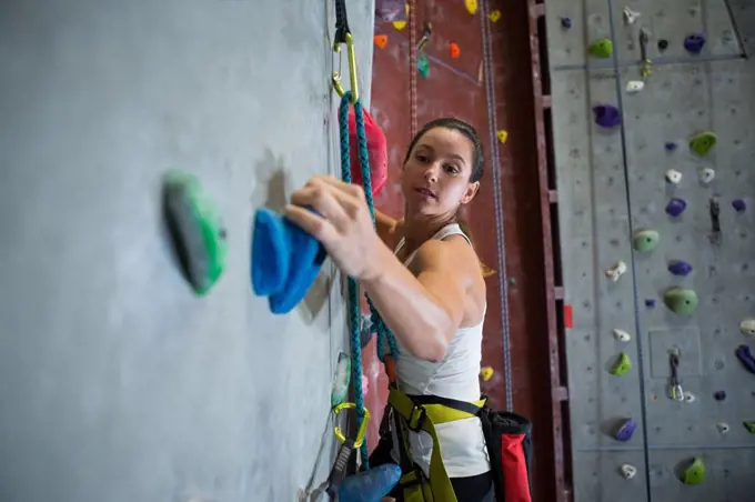 Determined woman practicing rock climbing in fitness studio