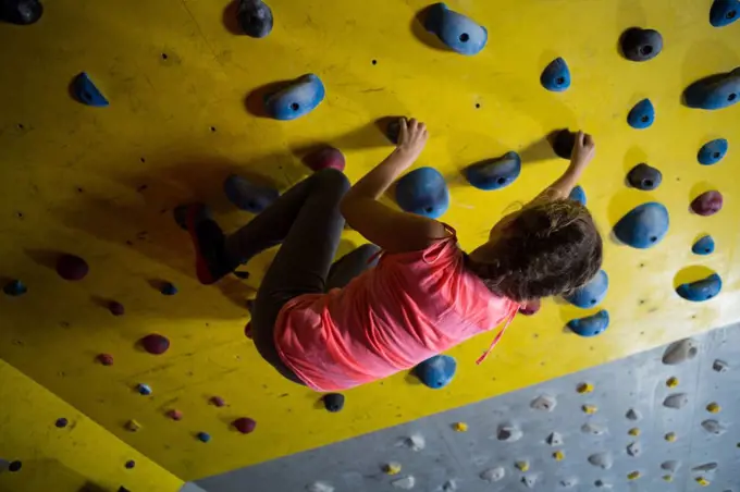 Teenage girl practicing rock climbing in fitness studio