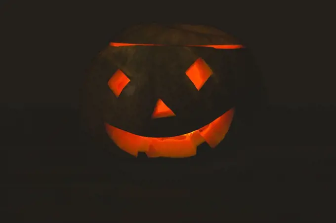 Close up of jack o lantern glowing in darkroom