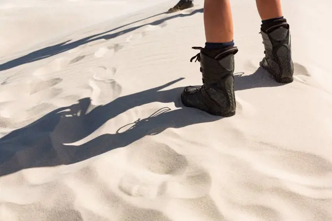 Low section of person standing in sand on a sunny day