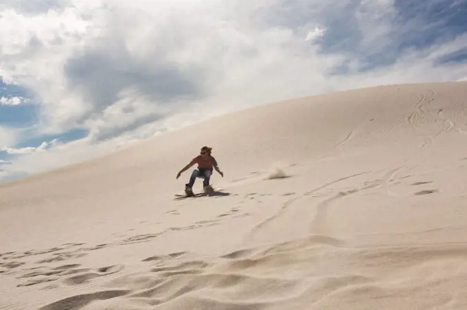 Woman sandboarding on sand dune at desert