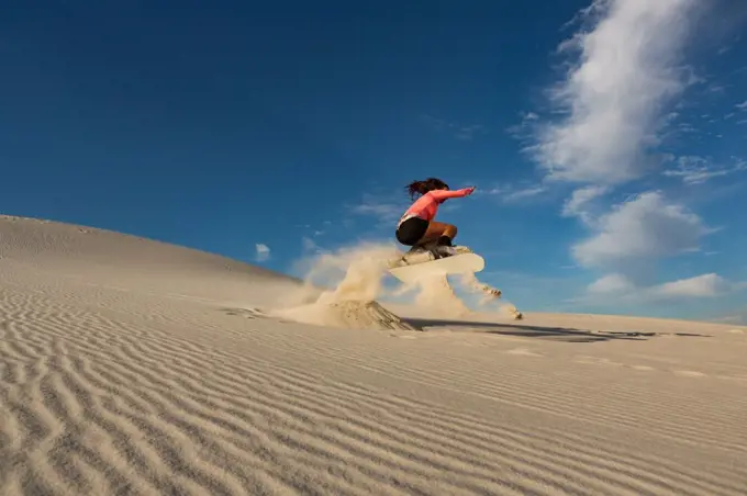 Woman sandboarding on sand dune at desert