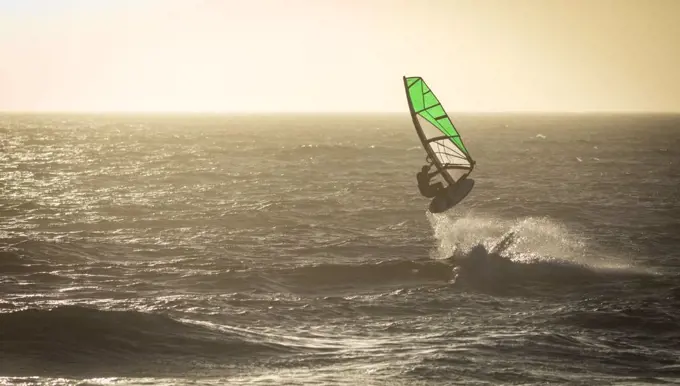 Male surfer surfing with surfboard and kite at beach