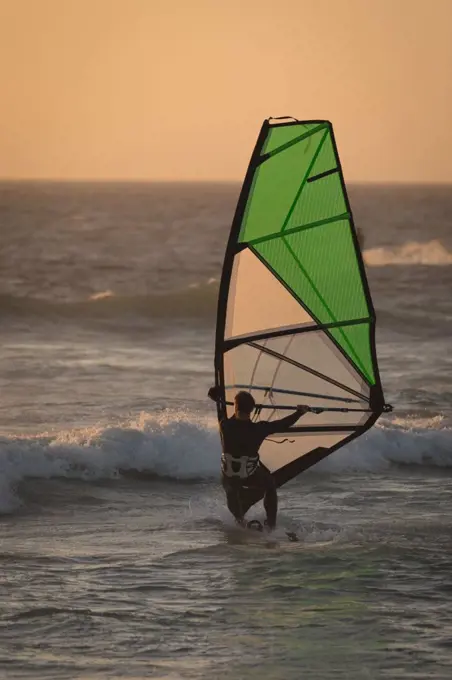 Male surfer surfing with surfboard and kite at beach