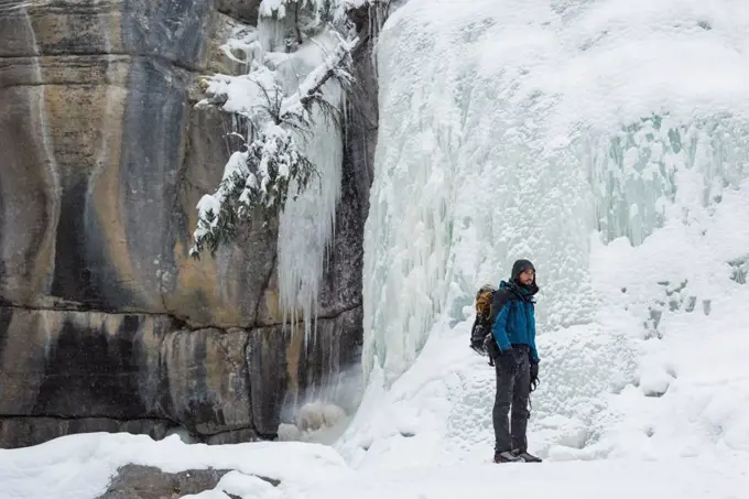 Male climber standing near rocky mountain during winter