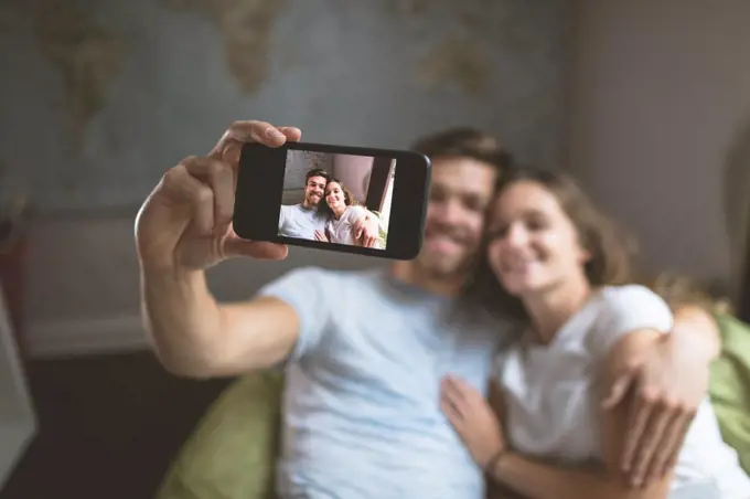 Couple taking selfie with mobile phone at home