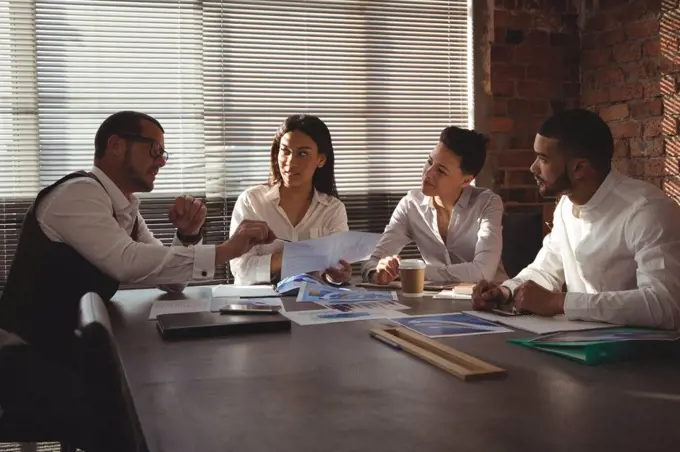 Executives discussing over document in conference room in office