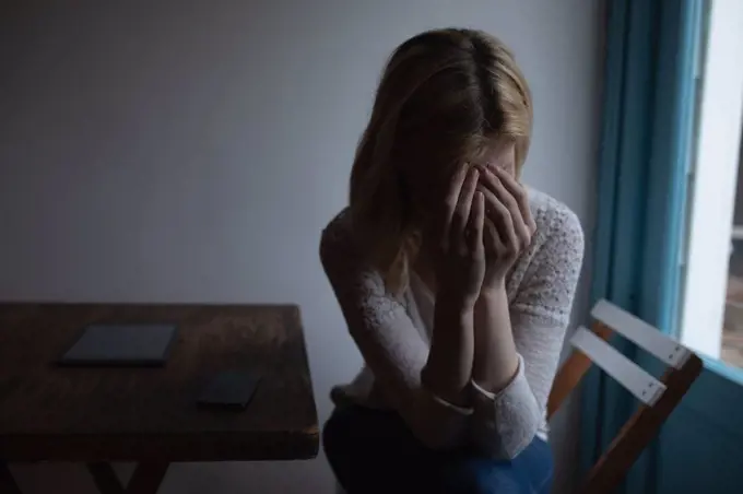 Worried woman sitting on chair at home