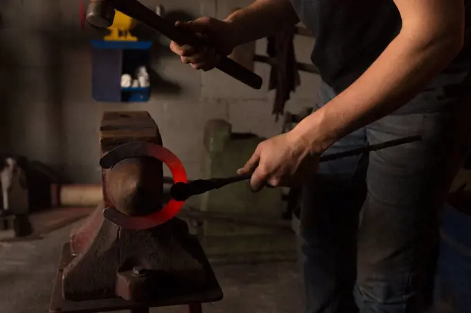 Mid section of female metalsmith molding horseshoe in factory