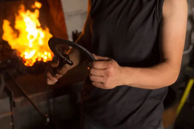 Mid section of female metalsmith molding horseshoe in factory