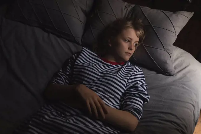 Thoughtful woman relaxing on bed in bedroom