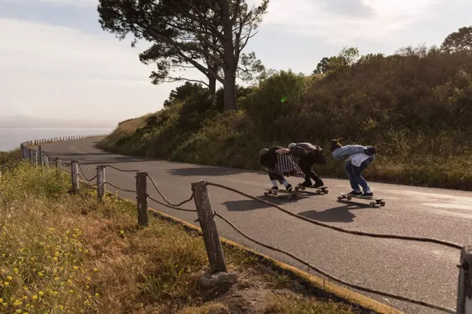 Skateboarders skating on downhill at countryside on a sunny day