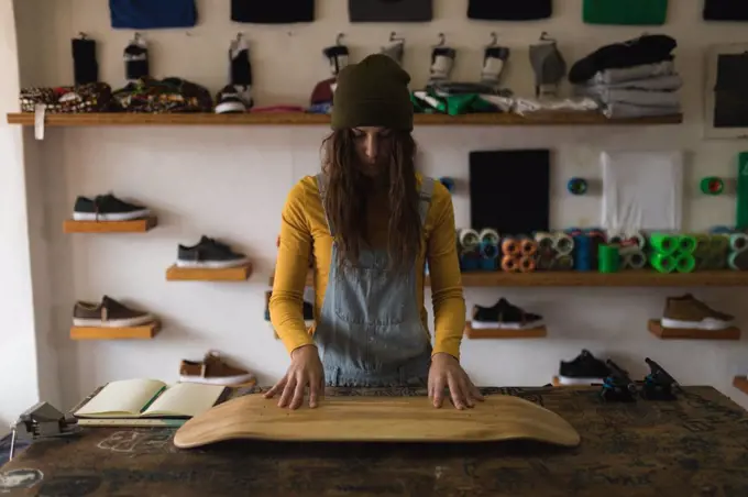 Young woman examining skateboard deck in workshop