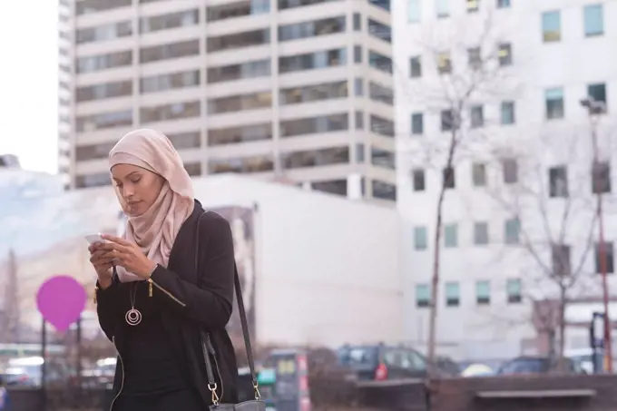 Hijab woman using mobile phone in city