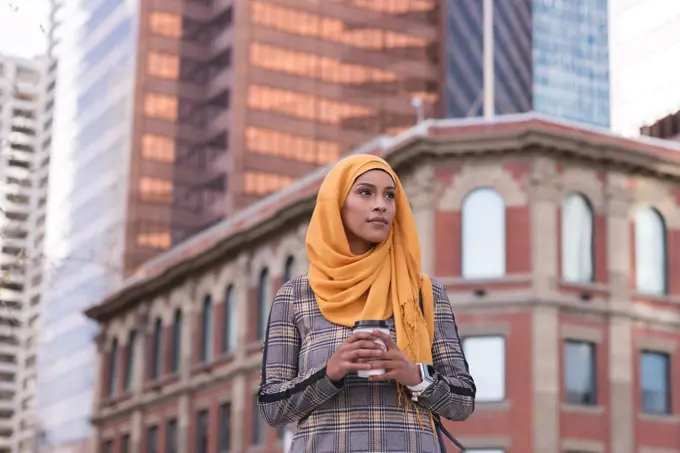 Thoughtful hijab woman having coffee in city