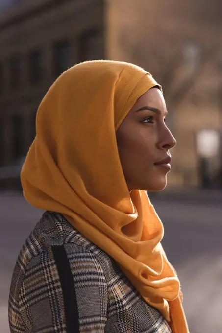 Thoughtful hijab woman standing in city