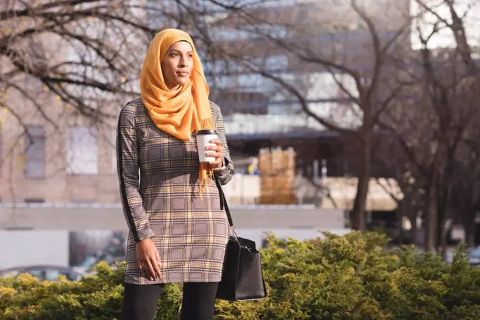 Hijab woman having coffee in park