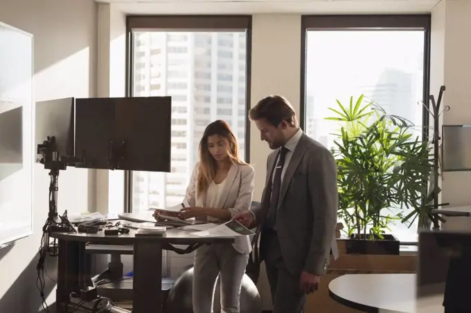 Side view of Standing business people discussing over documents in the modern office