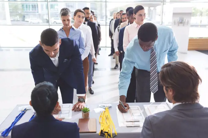 Front view of diverse business people checking in at conference registration table in office lobby