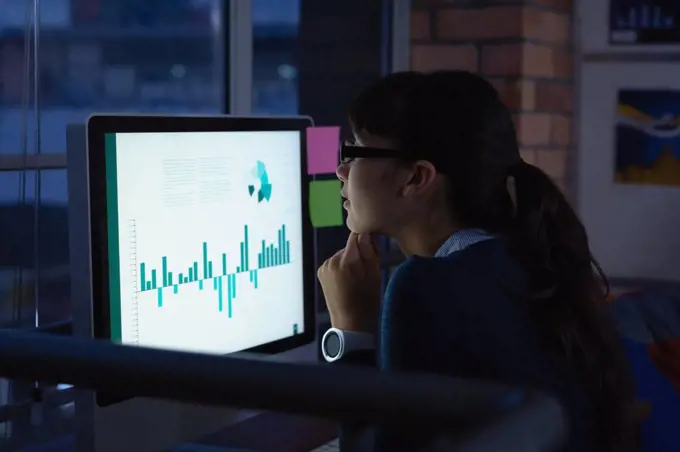 Side view of caucasian  businesswoman working over graph project in office at desk by night