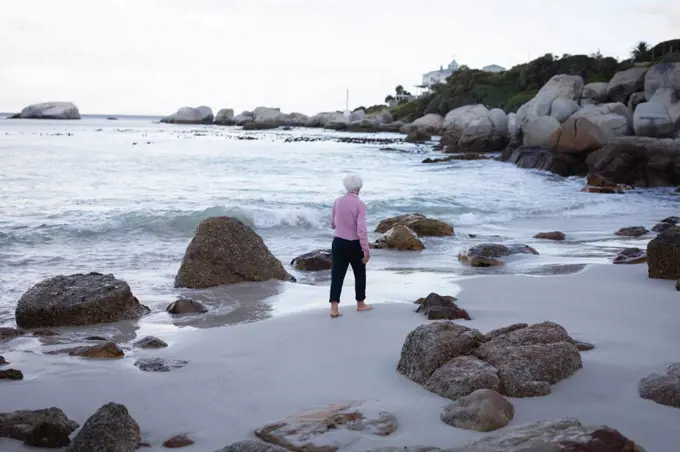 Rear view of an active Caucasian senior woman walking on the waterside of the beach