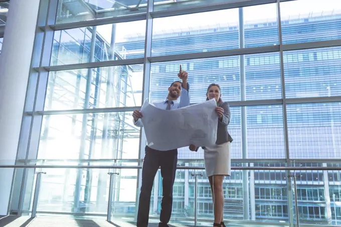 Low angle view of business people discussing over blueprint in a modern office building