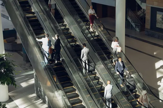 Aerial view of diverse business people using escalators in modern office 