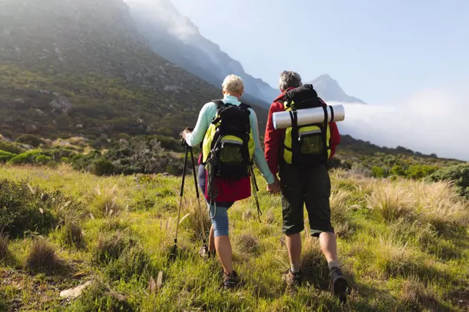 Senior couple spending time in nature together, walking in the mountains, holding hands. healthy lifestyle retirement activity.