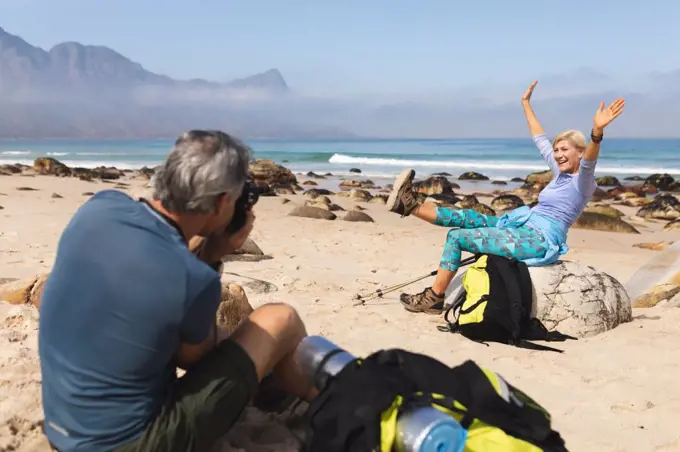 Senior couple spending time in nature together, walking on the beach, man is taking a picture of woman. healthy lifestyle retirement activity.