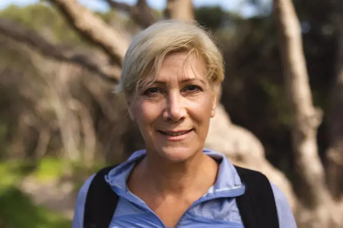 Portrait of a senior woman spending time in nature, walking in the mountains, looking at the camera and smiling. healthy lifestyle retirement activity.