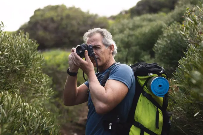 Senior man spending time in nature, walking in the mountains, taking a picture. healthy lifestyle retirement activity.