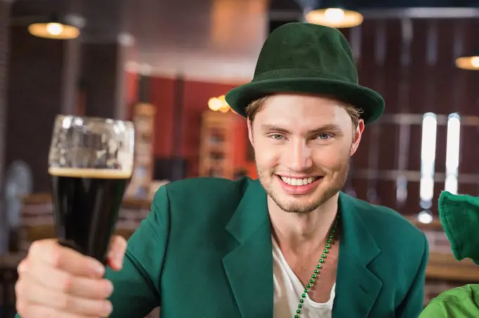 Man with a hat toasting a beer in a bar