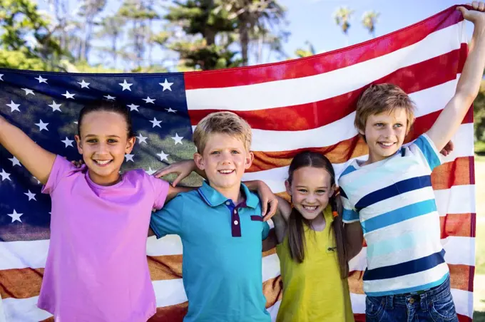 Portrait of children holding american flag in park