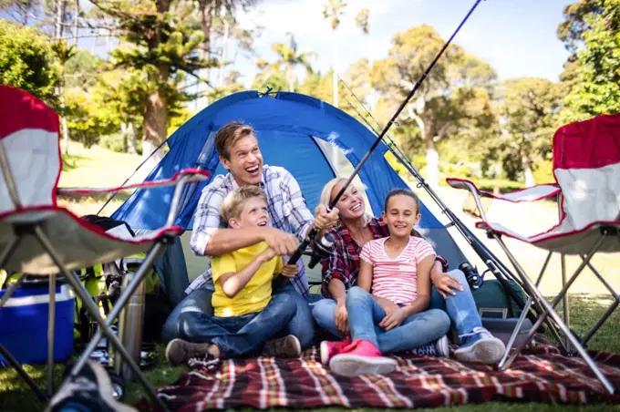 Family on a camping trip fishing outside their tent