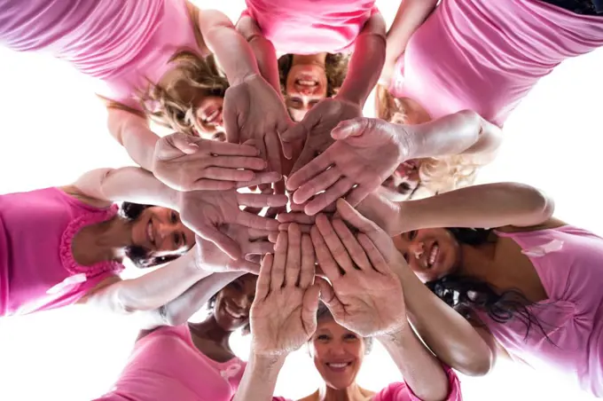 Women in pink outfits joining in a circle on white background for breast cancer awareness 