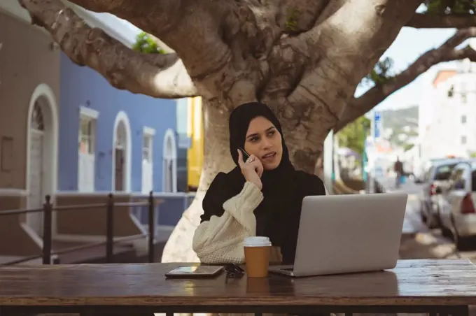 Beautiful urban hijab woman talking on mobile phone at cafe