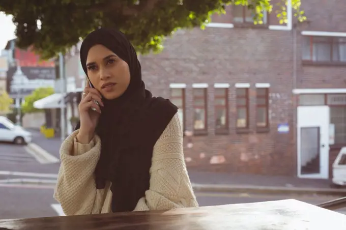 Beautiful urban hijab woman talking on mobile phone at cafe