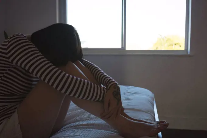 Worried woman sitting on bedroom at home