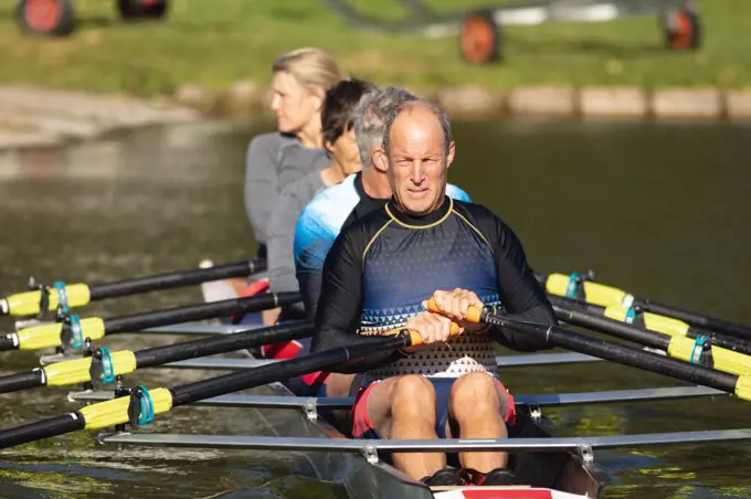 Senior caucasian rowing team rowing the boat on the lake. retirement sports and active senior lifestyle.