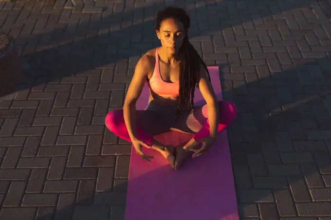 African american woman exercising on promenade by the sea doing yoga. fitness healthy outdoor lifestyle.