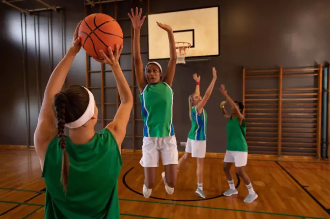 Diverse female basketball team practicing shooting with ball. basketball, sports training at an indoor court.