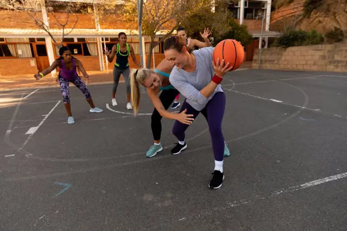 Diverse female basketball team wearing sportswear and practice dribbling ball. basketball, sports training at an outdoor urban court.