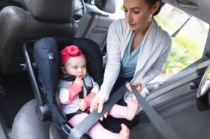 Caucasian mother putting her baby in safety baby seat in the car. motherhood, love and baby care concept