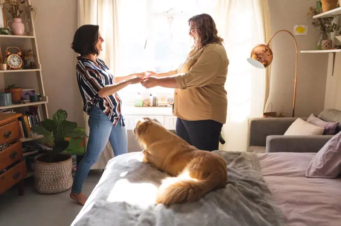 Happy lesbian couple holding hands and smiling in bedroom. domestic lifestyle, spending free time at home.