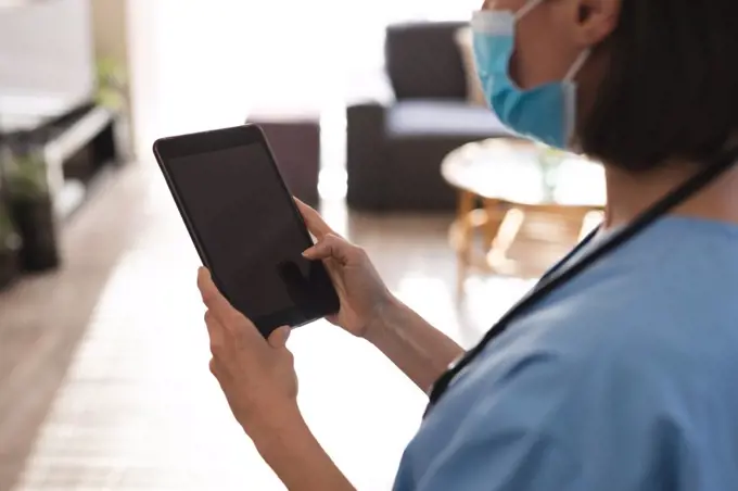 Caucasian female doctor wearing face mask and using tablet. medical and healthcare services during coronavirus covid 19 pandemic.