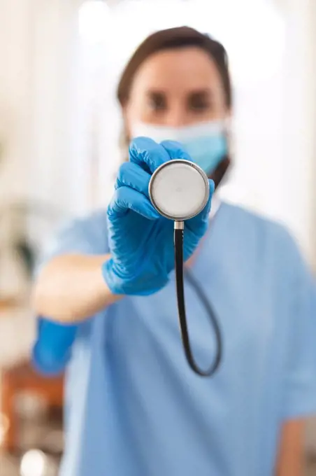 Portrait of caucasian female doctor wearing face mask and holding stethoscope. medical and healthcare services during coronavirus covid 19 pandemic.