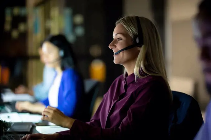 Caucasian businesswoman working at night wearing headset. working late in business at a modern office.