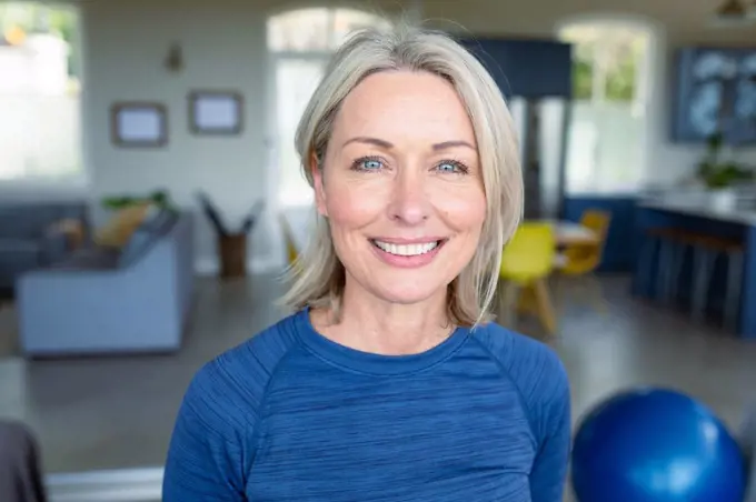 Portrait of happy senior caucasian woman in exercise clothes looking at camera and smiling. healthy, active retirement lifestyle at home.