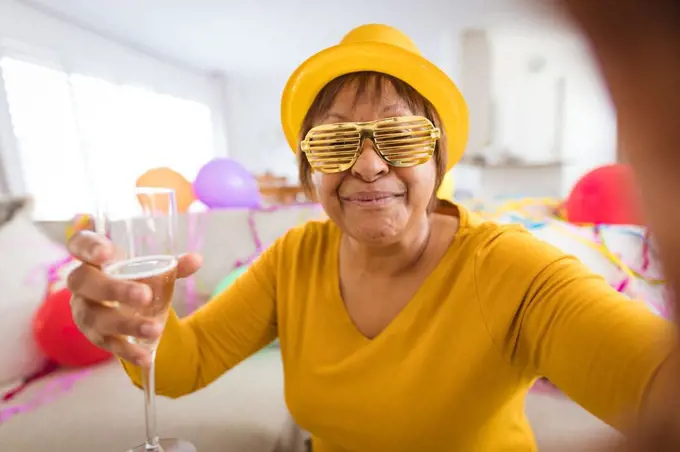 Senior woman in shutter glasses making video call while enjoying champagne during party at home. lifestyle, celebration, young at heart and communication.