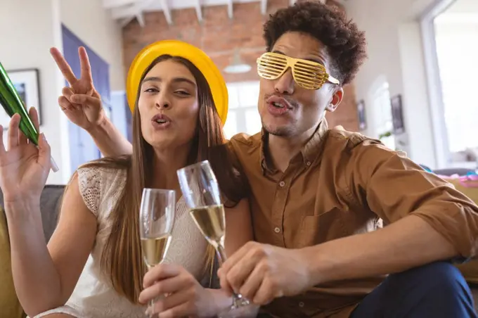 Portrait of happy biracial couple enjoying party with champagne flutes at home. celebration and lifestyle.